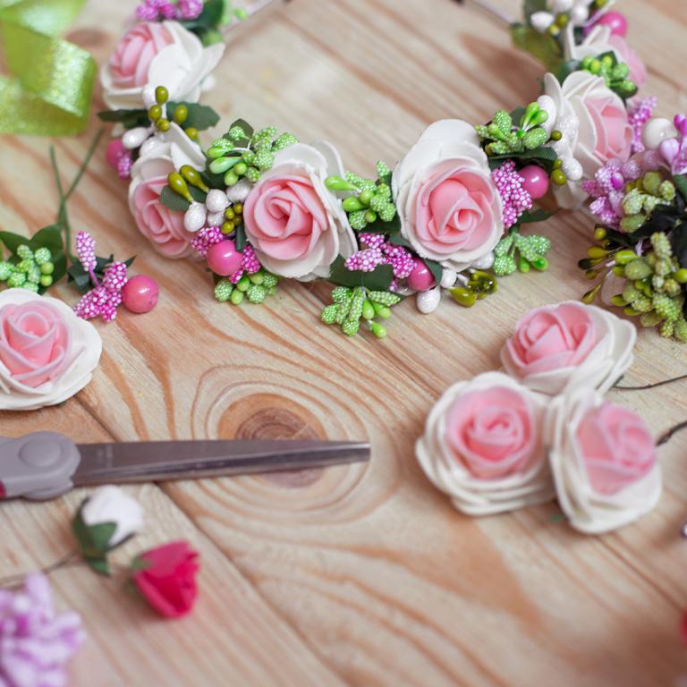 Table with flowers, glue gun and ribbon for DIY project