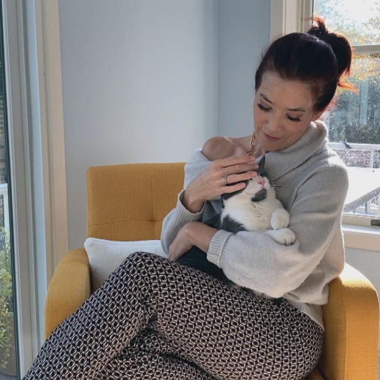 Amy E. Goodman wearing a sweater and looking comfy with her cat