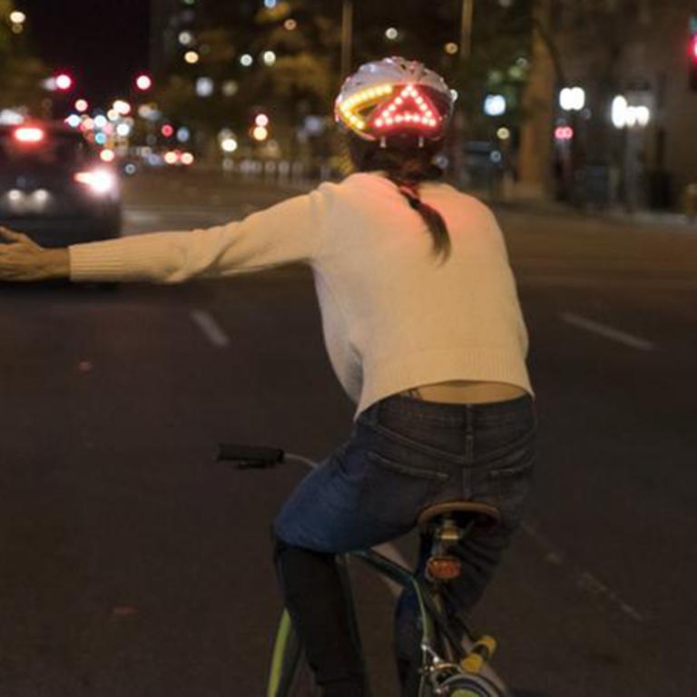 Woman on bike wearing Lumos smart bike helmet