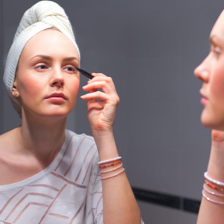 tired woman putting on eye makeup